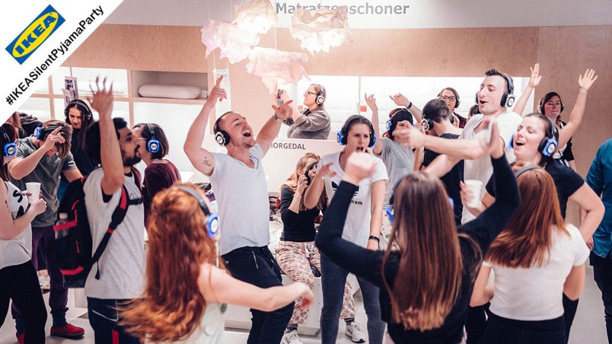 Viele Menschen tanzen bei einer Silent Pyjama Party mit Silent Disco Kopfhörern bei IKEA.