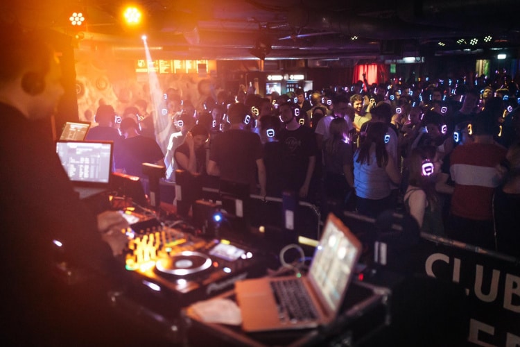 Party Crowd und DJ auf einer Silent Disco Party im Club mit Neon Lights Kopfhörern