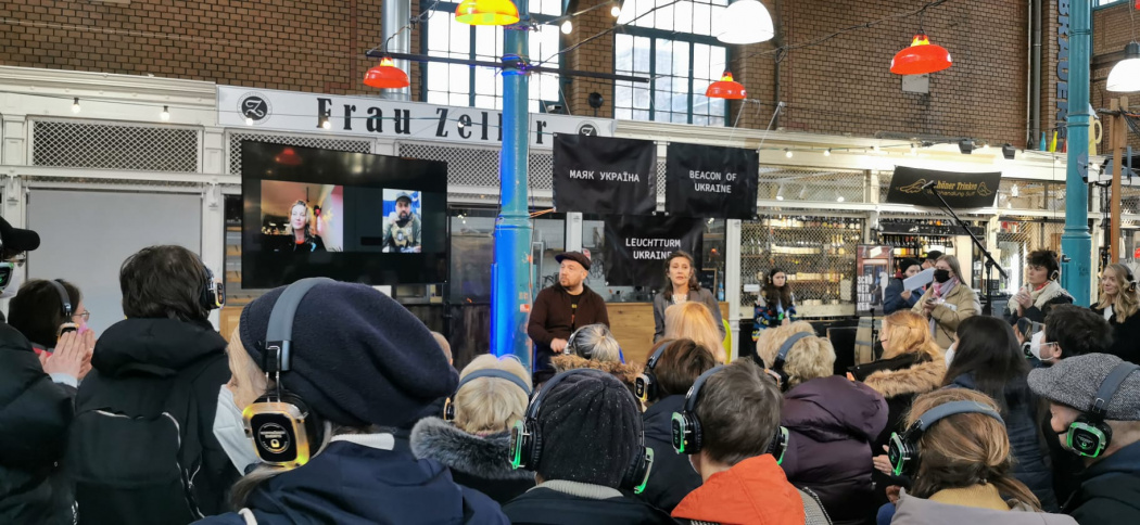 Gäste des Leuchtturm Ukraine Projekts Berlin hören Vortrag mit Neon Lights Kopfhörern