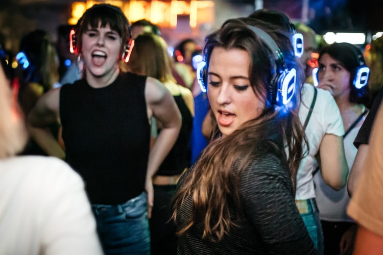 Tanzende junge Menschen auf einer Club Kopfhörerparty mit Silent Disco Kopfhörern