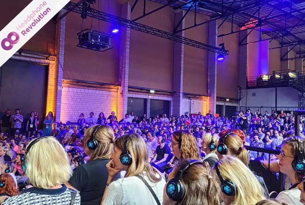 Sehr viele Menschen hören bei einer Silent Conference in der Arena Berlin einem Vortrag zu und tragen dabei Silent Kopfhörer von Headphone Revolution.