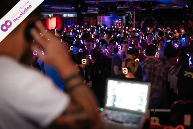 Ein DJ und viele Besucher bei einer Silent Disco in einem Club mit Neon Lights Kopfhörern von Headphone Revolution.