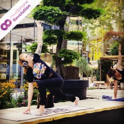 Frauen machen auf einer Bühne beim YEZ Yoga Festival mit Yogaübungen, bei denen der Ton der Fitness Trainerin über spezielle Silent Kopfhörer übertragen wird.