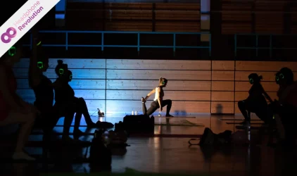 Menschen beim Yoga in einer Sporthalle tragen Silent Kopfhörer von Headphone Revolution.