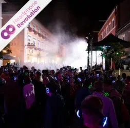 Viele Menschen nehmen bei einer Open Air Silent Disco teil und tanzen zur Musik auf den Silent Disco Kopfhörern.