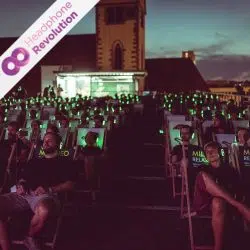 Viele Besucher des Bunter Beton Festivals sitzen in Liegestühlen und tragen das Silent Kopfhörer Modell "HR T12 Pro" von Headphone Revolution, um so die Live-Musik der Bands hören zu können.