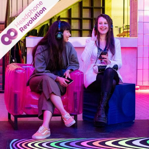 Zwei Frauen tragen spezielle Silent Conference Kopfhörer auf einer Messe.