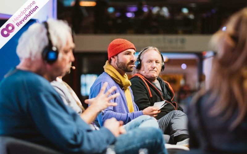 Personen, die bei einer Diskussion Silent Kopfhörer und Headset Mikrofone tragen, damit das Publikum den Ton besser hören kann.