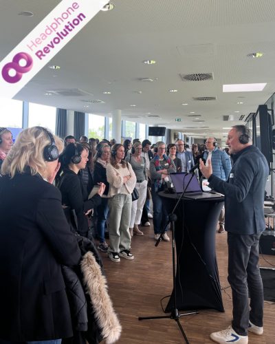 Ein Mann hält einen Vortrag bei einem Workshop, bei dem statt Flüsteranlage eine Silent Conferencing System von Headphone Revolution verwendet wird.