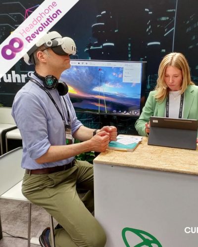 Menschen an einem Messestand auf dem Ruhr Summit tragen Silent Conference Kopfhörer um den Ton der Vorträge zu hören.