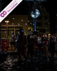 Einige Menschen feiern im Regen eine Kopfhörerparty und hören die verschiedenen Musikrichtungen über die Silent Disco Kopfhörer von Headphone Revolution.