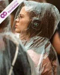 Eine Silent Disco Besucherin trägt im Regen einen Regenponcho und hört dabei Musik, welche über ein spezielles Silent Disco Kopfhörersystem übertragen wird.