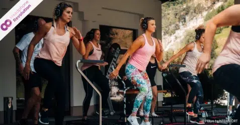 Ein Gruppe Menschen bei einem Fitness Jumping Kurs von Intersport trägt spezielle Silent Disco Kopfhörer von der Firma Headphone Revolution über welche die Anweisungen der Trainerin und Musik übertragen werden.