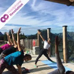 Menschen, die bei einem Silent Yoga Kurs in den Bergen teilnehmen und dabei das Neon Lights Kopfhörer System von Headphone Revolution nutzen.