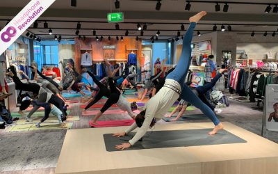 Einige Menschen, die mit Silent Fitness Kopfhörern an einem Yoga-Kurs in einem Einkaufszentrum teilnehmen.