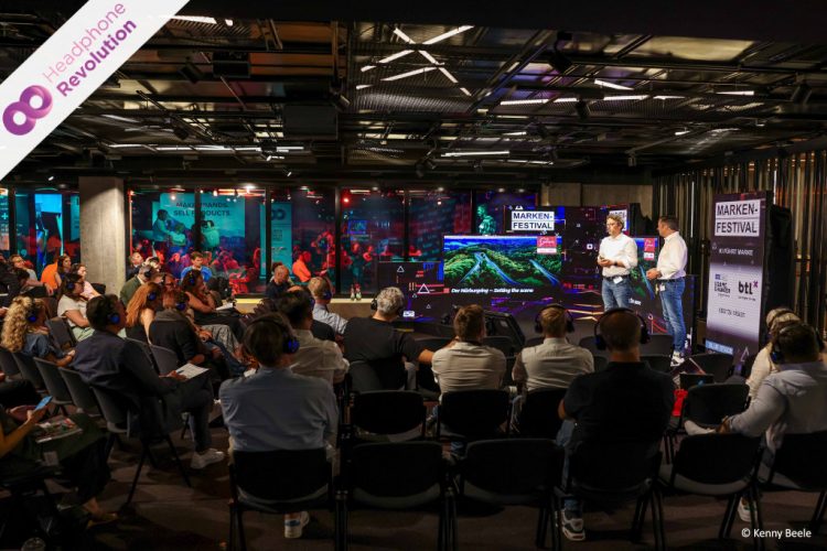 Besucher eines Vortrags während des Markenfestivals 2024 tragen spezielle Silent Conference Kopfhörer über die der Ton der Referenten übertragen wird.