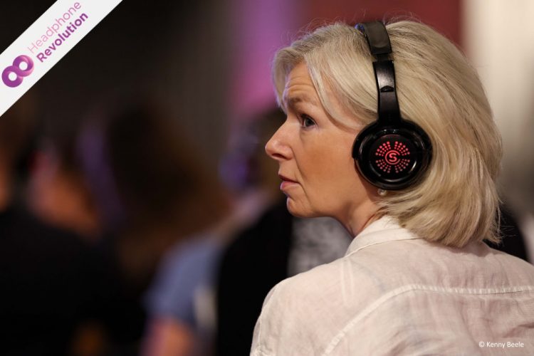 Eine Besucherin des ESB Markenfestivals in Düsseldorf trägt rot leuchtende Silent Conference Kopfhörer von Headphone Revolution