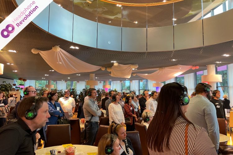 Viele Teilnehmer einer Silent Conference hören einem Vortrag zu, bei dem der Ton über ein spezielles Silent Conference Kopfhörersystem übertragen wird.