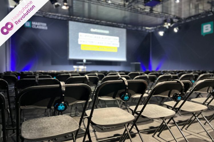 Silent Conference Kopfhörer "HR SC Flex" von Headphone Revolution verteilt auf Stühlen vor einer Bühne auf dem OMR Festival