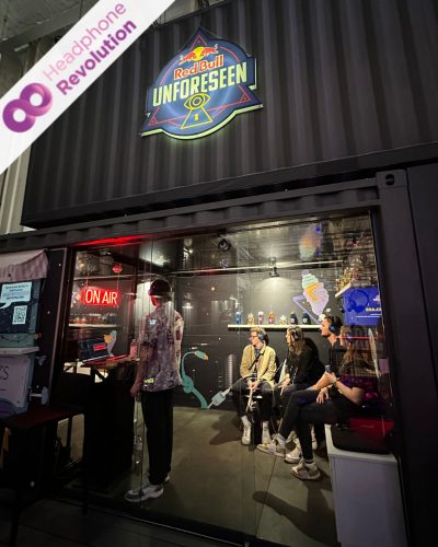 Menschen, die Silent Conference Kopfhörer tragen und bei einem Live-Podcast von Podstars am Red Bull Stand auf dem OMR Festival zuhören.