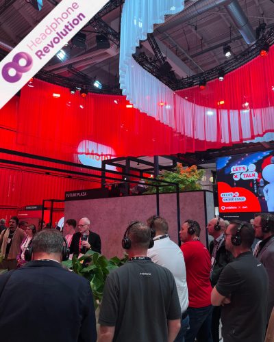 Viele Menschen tragen gebrandete Silent Conference Kopfhörer am Vodafone Stand auf der OMR 2024 in Hamburg um den gesprochenen Ton eines Speakers besser zu verstehen.