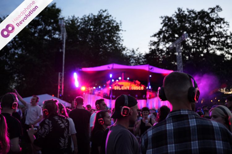 Viele Menschen feiern bei einer Silent Disco vor der Bühne und hören die Musik über Silent Disco Kopfhörer von Headphone Revolution.