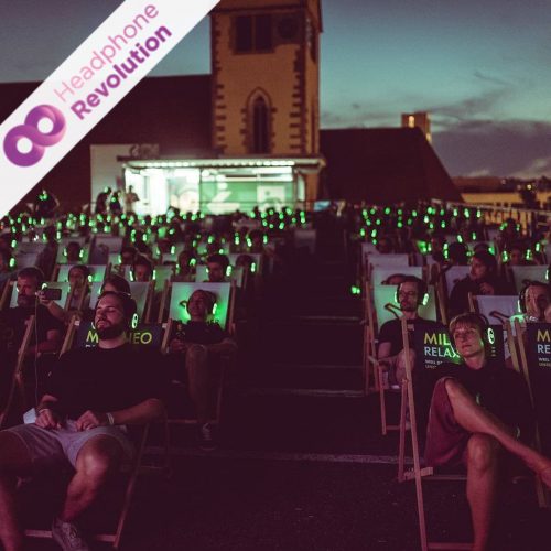 Eine Menge von Menschen, die in Liegestühlen liegt und HRT12PRO Kopfhörer tragen, während sie ein Silent Concert anschauen