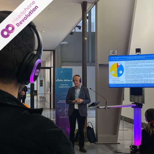 Ein Besucher einer Silent Conference, der während der Vortrag des Sprechers im Hintergrund HRT12PRO-Kopfhörer trägt